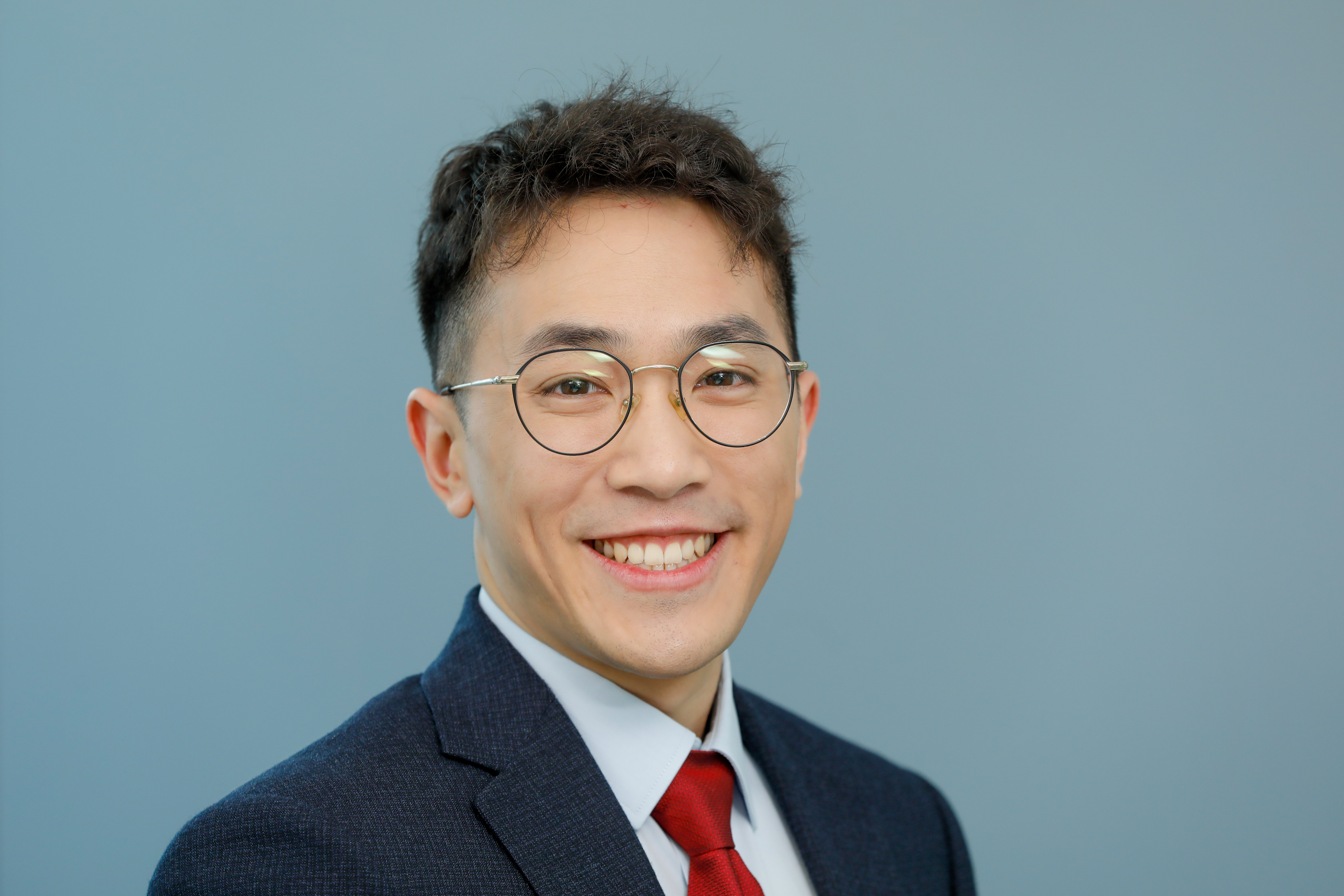 Professional headshot of a man in a suit smiling